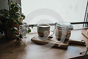 High angle view of tiramisu in glass cup with coffee cappuccino. In vegsn shop, local cozy cafe. Wooden background, candid style.