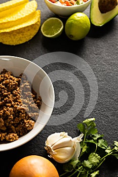 High angle view of tortillas, meat, avocado, lemon, cilantro, tomato and garlic on table