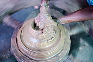 High angle view , unrecognizable potter making clay pot by moulding on traditional cart wheel - concept of handcraft