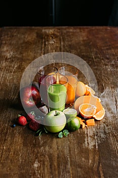 high angle view of various smoothies in glasses and fresh fruits with vegetables on wooden