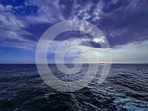 High angle view from a wavy sea against dramatic cloud sky at sunset