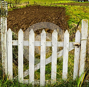 High angle view of the white wooden fence protecting the entrance to the field on a sunny day