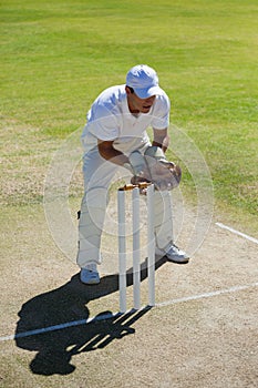 High angle view of wicketkeeper standing behind stumps on field