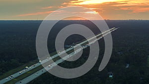 High angle view of wide congested american highway with many driving cars and trucks at sunset. Concept of interstate