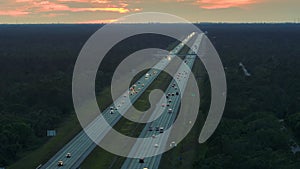 High angle view of wide congested american highway with many driving cars and trucks at sunset. Concept of interstate