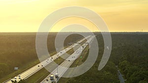 High angle view of wide congested american highway with many driving cars and trucks at sunset. Concept of interstate