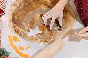 High angle view of a woman cutting gingerbread biscuits into cooking dough