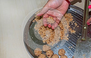 High angle view of a woman making homemade sweet, coconut laddu for festive season on a domestic table. Close up and selective