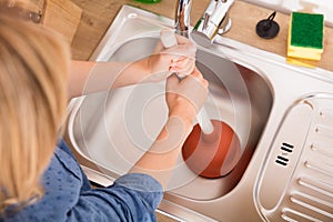 High Angle View Of Woman Using Plunger In Sink