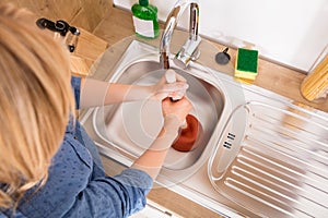 High Angle View Of Woman Using Plunger In Sink