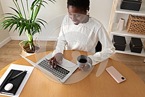 High angle view of young african american woman working at home office. Happy Black female entrepreneur using laptop.
