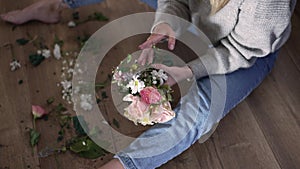 High angle view young barefoot woman gathering broken bouquet of flowers in slow motion. Unrecognizable Caucasian lady