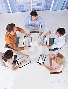 High angle view of young business people discussing on graphs at table in office
