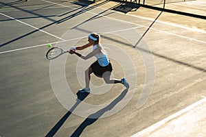 High angle view of young female caucasian tennis player hitting ball at court on sunny day