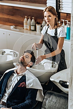 High angle view of young hairdresser washing hair to handsome client