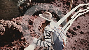 High angle view of young happy female tourist with backpack and arms wide open at the edge of Vesuvius volcano crater.