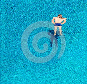 High angle view of young man sleeping on lifebuoy in swimming pool
