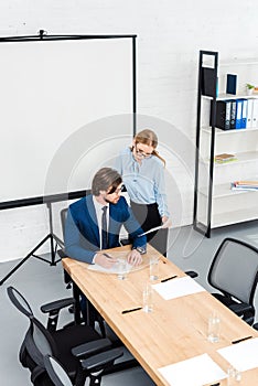 high angle view of young manageress showing documents to her boss