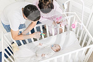 High angle view of young parents looking at baby in crib