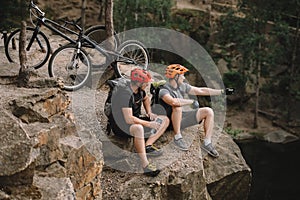 high angle view of young trial bikers relaxing on rocky cliff after ride