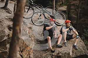 high angle view of young trial bikers relaxing on rocky cliff after ride