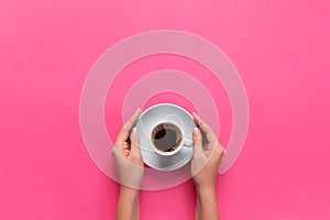 High angle of woman hands holding coffee cup on pink background Minimalistic style. Flat lay, top view isolated