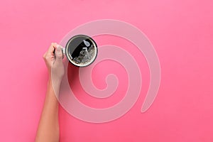 High angle of woman hands holding coffee mug on pink background Minimalistic style. Flat lay, top view isolated photo