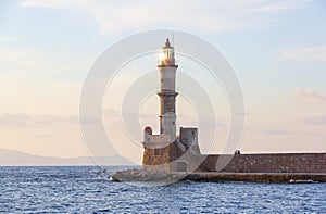 High, beautiful, ancient lighthouse made of bricks. Marvelous sunset lights the sky. Local place Chania, Creete island, Greece.