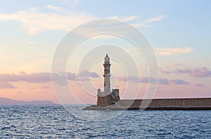 High, beautiful, ancient lighthouse made of bricks. Marvelous sunset lights the sky. Touristic resort Chania, Creete island Greece