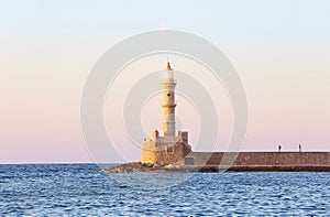 High, beautiful, ancient lighthouse made of bricks. Marvelous sunset lights the sky. Touristic resort Chania, Greece.