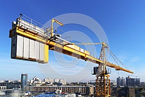 High building construction site. Big industrial tower crane with blue sky amd cityscape on background. Concrete plates weight bala