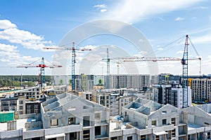 High building tower cranes at construction site against blue sky background