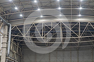 High-ceilinged interior with metal beam grid, artificial diffused lighting, empty foreground, geometric patterns, smooth