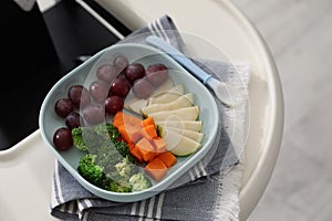 High chair with food in baby tableware on tray indoors, closeup. Above view