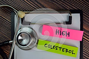 High Colesterol write on sticky notes isolated on Wooden Table. Medical or Healthcare concept