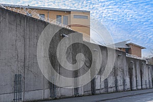 high concrete fence, barbed wire fence on top, pre-trial detention cell, building for execution of punishments for criminals,