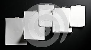 Five empty notes taped on a dramatic black surface