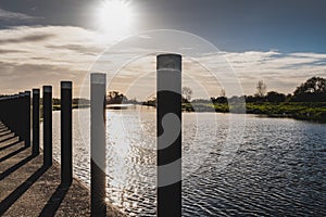 High contrast view of an autumn sunset seen casting shadows against mooring poles seen at a jetty.