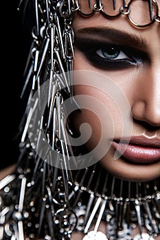 High fashion beauty model with metallic headwear and dark makeup and blue eyes on black background