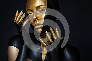 High fashion model with black and gold leather, golden fingers.