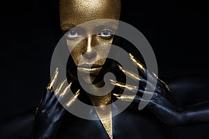 High fashion model with black and gold leather, golden fingers. Isolated on black background Beauty female face,