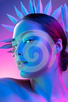 High fashion model in colorful bright neon lights posing at studio. Portrait of beautiful girl with trendy glowing make