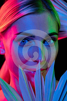 High fashion model in colorful bright neon lights posing at studio. Portrait of beautiful woman with trendy glowing make