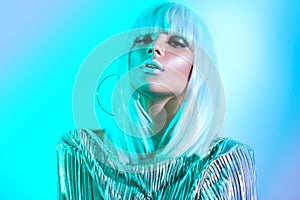 High fashion model girl in colorful bright neon lights posing in studio. Portrait of beautiful woman in white wig