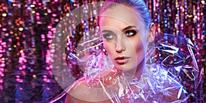 High Fashion model girl in colorful bright neon lights posing in studio through transparent film. Portrait of beautiful