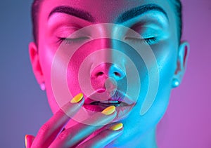 High Fashion model girl in colorful bright UV lights posing in studio, portrait of beautiful woman with trendy makeup and manicure
