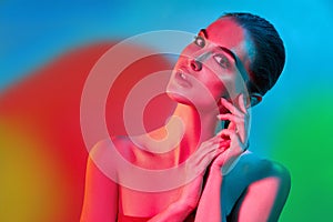 High Fashion model woman in colorful bright lights posing in studio