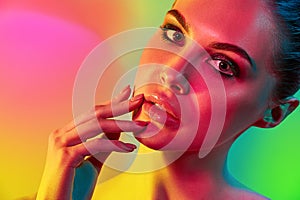 High Fashion model woman in colorful bright lights posing in studio