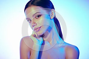 High Fashion model woman in colorful bright lights posing in studio