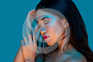 High Fashion model woman in colorful bright lights posing in studio